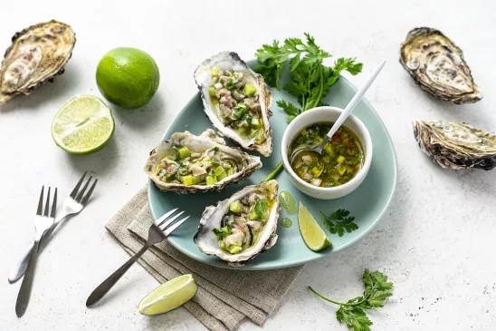 Assiette avec 3 huîtres garnies d'un mélange de concombre et citron vert. Une recette fraîche et d'été.
