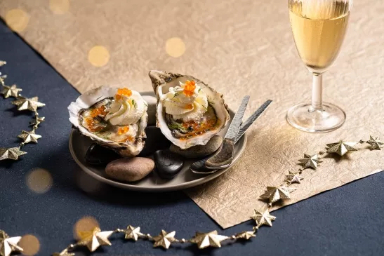 Une assiette deux huîtres dans lesquelles il y a de la chantilly et des œuf de poisson. Accompagnée d'un champagne, cette recette est autant festive que iodée.